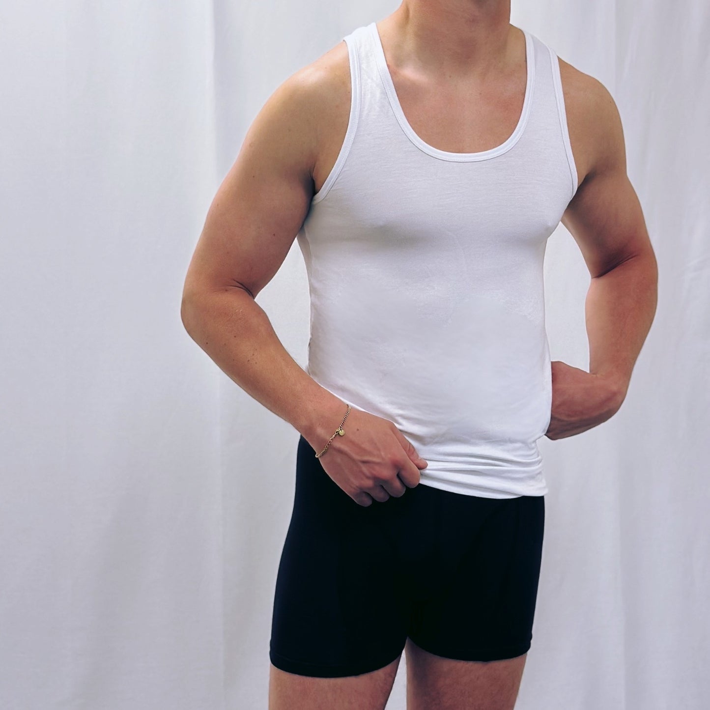 Man wearing a white tank top and black boxershorts, showcasing comfortable men’s underwear.