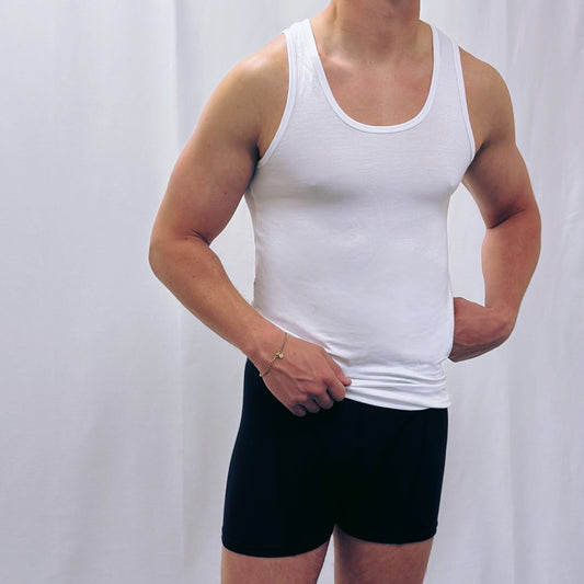 Man wearing a white tank top and black boxershorts, showcasing comfortable men’s underwear.